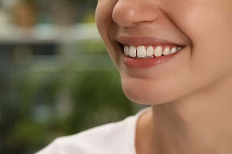 Woman with diastema between upper front teeth on blurred backgro