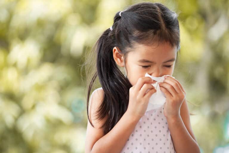 Sick asian little child girl wiping and cleaning nose with tissu