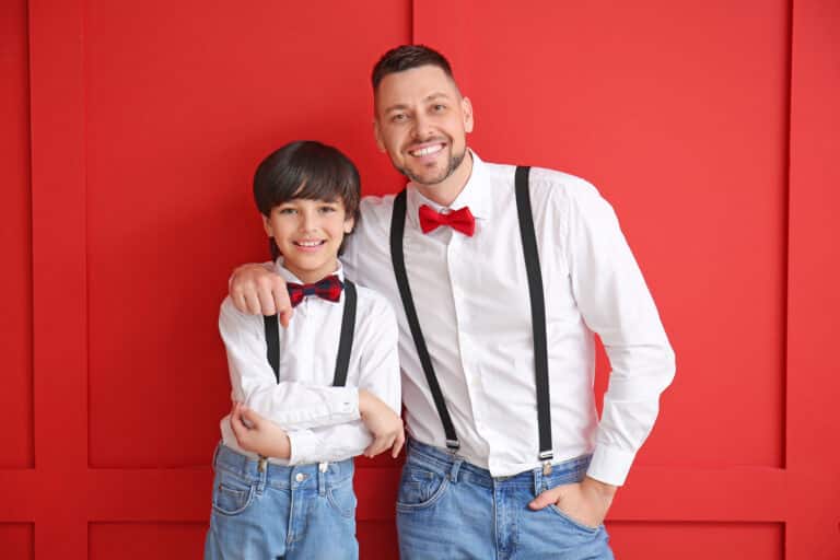 Stylish father and little son on color background