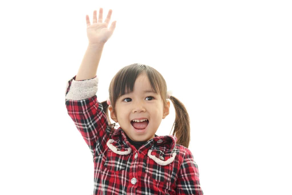 手を挙げて返事している笑顔の園児