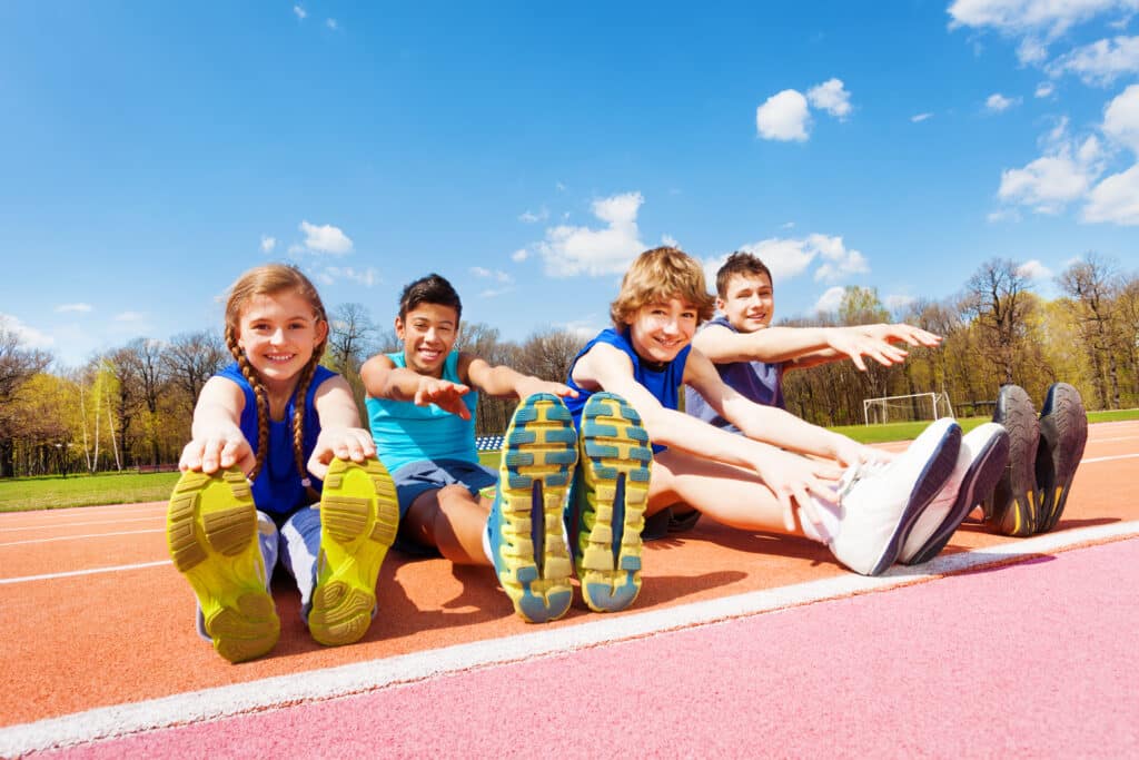 Happy kids doing stretching exercises on a stadium