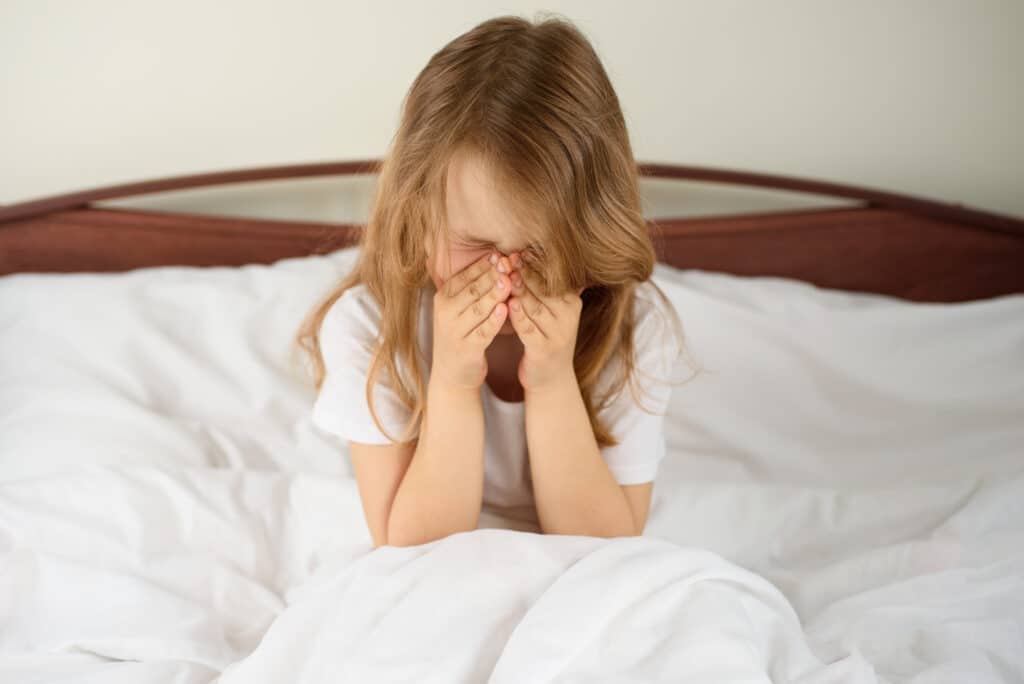A little girl sits and sneezes